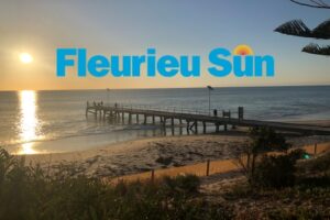 Sun sitting above water with jetty in foreground and Fleurieu Sun logo superimposed