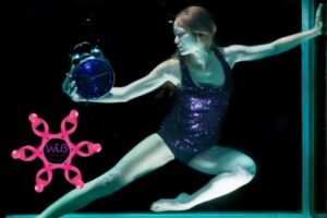 Woman holding clock in ballet pose while underwater.