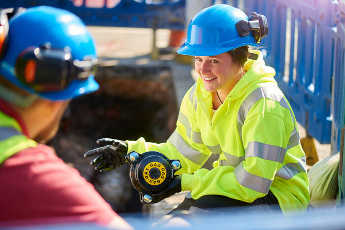 Young female apprentice in hi-vis jacket and hard hat.